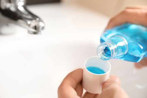 Man,Pouring,Mouthwash,From,Bottle,Into,Cap,In,Bathroom,,Closeup.