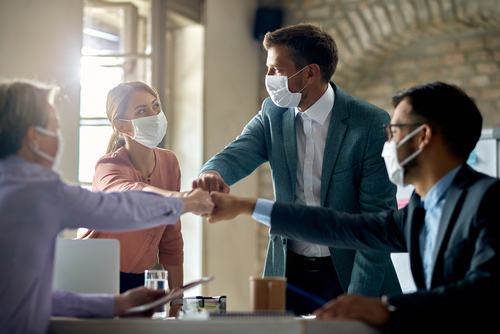 Group,Of,Colleagues,Wearing,Protective,Face,Masks,And,Fist,Bumping