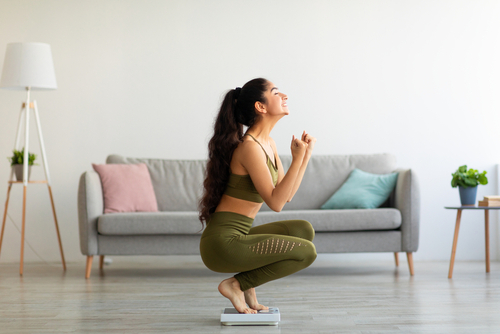 Full,Length,Of,Excited,Indian,Woman,Sitting,On,Scales,At