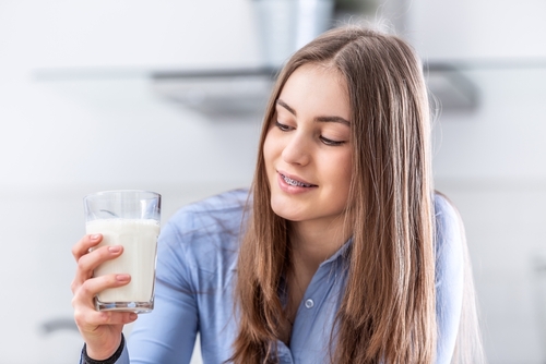 Young,Teenage,Girl,With,Dental,Braces,Holding,Cup,With,Milk.