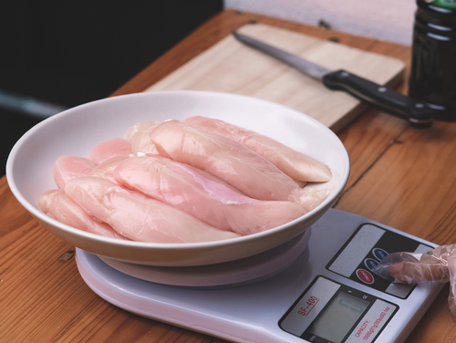 Woman,In,Gloves,Puts,Raw,Chicken,Breasts,In,A,Plate