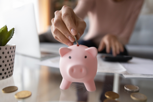Close,Up,Young,Female,Putting,Coin,In,Piggy,Bank.,Woman