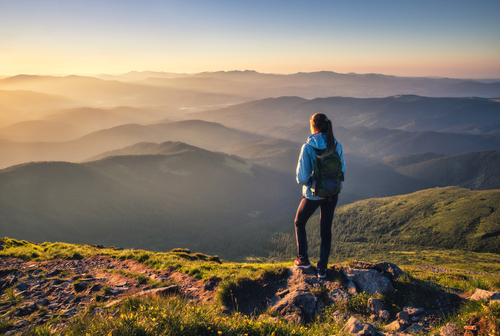 Girl,On,Mountain,Peak,With,Green,Grass,Looking,At,Beautiful
