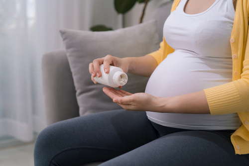 Pregnant,Woman,Holding,Plastic,Jar,With,Pills,,Taking,Vitamins,And