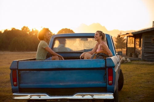 Two,Women,Riding,In,Back,Of,Pick,Up,Truck,As
