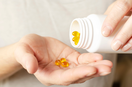 Caucasian,Female,Hands,With,Yellow,Pills,And,Medicine,Bottle,Closeup