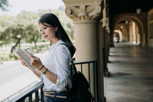 Young,Elegant,Student,Woman,Reading,Textbook,Outside,Classroom,At,School