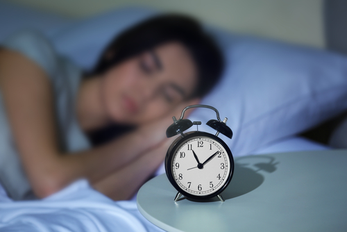 Young,Woman,Sleeping,In,Bed,With,Alarm,At,Night