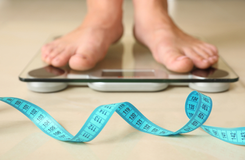 Tape,In,Front,Of,Woman,Standing,On,Floor,Scales,Indoors.