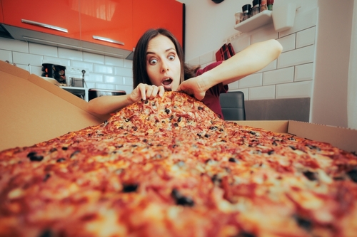 Hungry,Woman,Eating,A,Large,Pizza,By,Herself,In,The