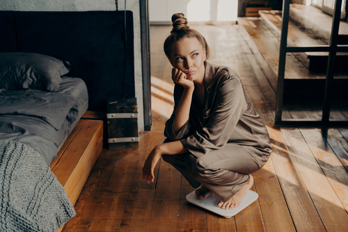 Upset,And,Unmotivated,Woman,On,Electronic,Floor,Scale,In,Bedroom